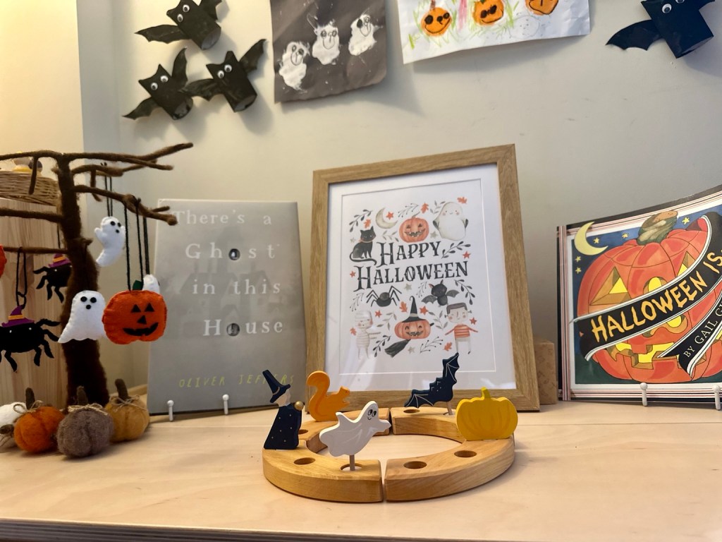 Halloween-inspired seasonal display with wooden celebration ring, hanging decorations and children's books